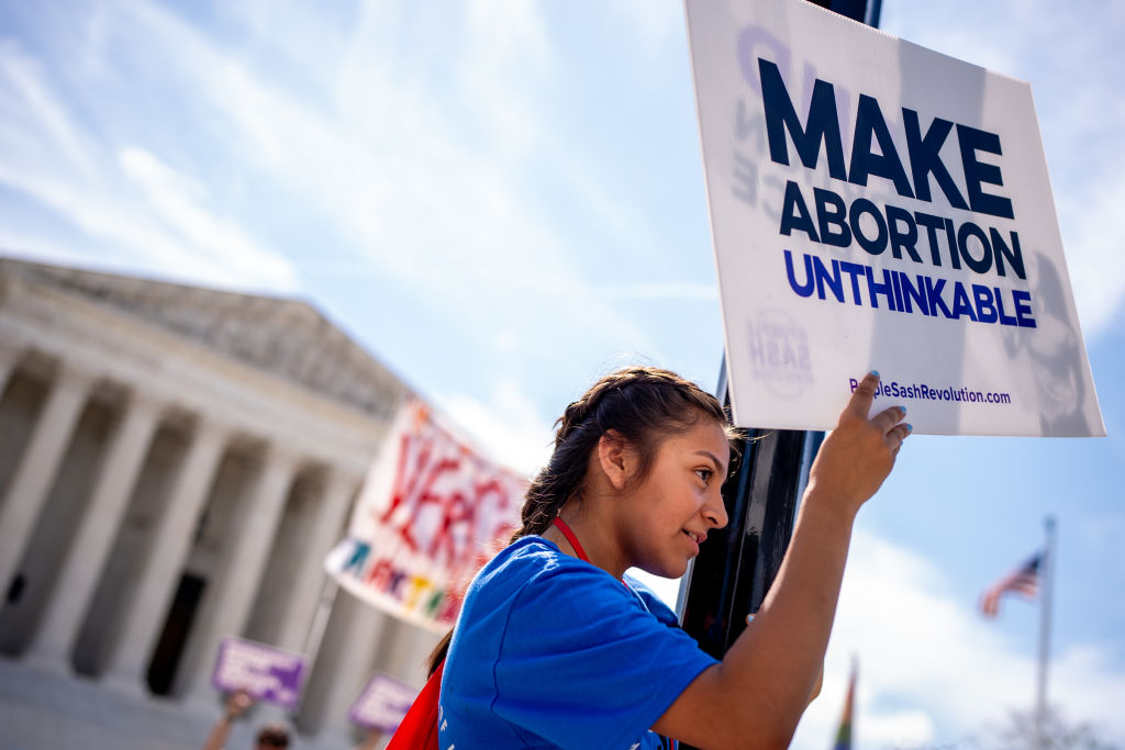 WASHINGTON, DC - JUNE 20: A pro-life supporter stands on a lamppost and holds a sign that reads "MAKE ABORTION UNTHINKABLE" in front of the Supreme Court on June 20, 2024 in Washington, DC. The Supreme Court issued four rulings today including upholding a tax on foreign income, but has not yet announced rulings on a variety of high profile cases dealing with abortion rights, gun rights, and former President Donald Trump's immunity claim. (Photo by Andrew Harnik/Getty Images)