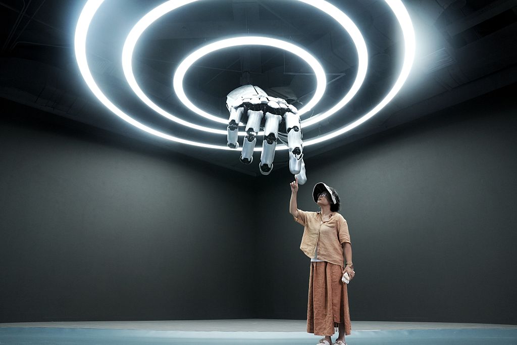 BEIJING, CHINA - AUGUST 4: A visitor interacts with a mechanic hand at the Robot Mall, world's first embodied intelligent robot 4S store, on August 4, 2025 in Yizhuang district, Beijing, China. The facility is scheduled to open in a robotics industrial park in Yizhuang, located in southern Beijing, during the 2025 World Robot Conference, which is set for August 8-12. (Photo by Zhang Xiangyi/China News Service/VCG via Getty Images)