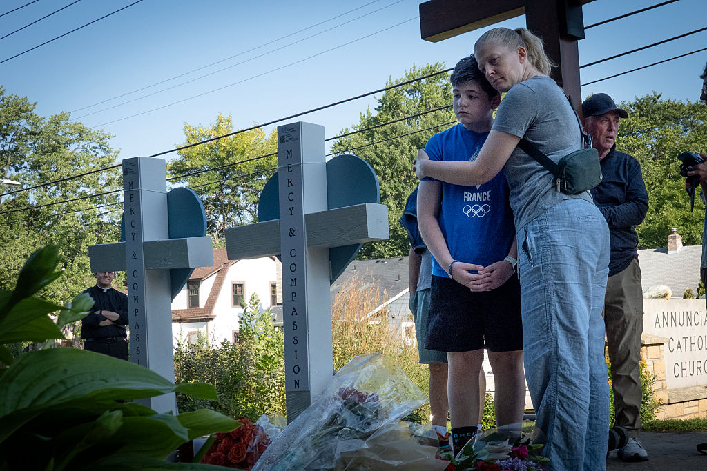 MINNEAPOLIS, MINNESOTA - AUGUST 28: People visit a memorial to yesterday's shooting victims in front of Annunciation Catholic Church on August 28, 2025 in Minneapolis, Minnesota. A gunman fired through the windows of the church while students were sitting in pews during a Catholic school Mass, killing two children and injuring at least 17 others. The gunman reportedly died at the scene from a self-inflicted gunshot wound, according to police. (Photo by Scott Olson/Getty Images)