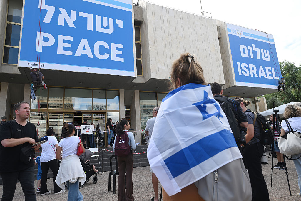 TEL AVIV, ISRAEL - OCTOBER 12: Workers put up pieces of a huge sign that reads, “Peace Israel” in English and in Hebrew on a building in hostage square on October 12, 2025 in Tel Aviv, Israel. This week's ceasefire deal between Israel and Hamas has brought an end to the two years of war that followed the attacks of Oct. 7, 2023. A condition of the deal is the return of 48 hostages held in Gaza, 20 of whom are believed to be alive. (Photo by Alexi J. Rosenfeld/Getty Images)