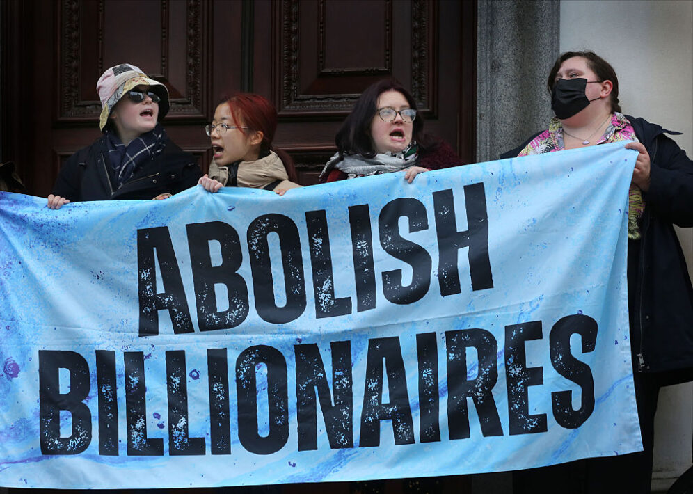 LONDON, ENGLAND - NOVEMBER 24: Protesters block one of the entrances to HM Treasury with a banner saying 'Abolish Billionaires' during a protest calling for a wealth tax outside the Treasury on November 24, 2025 in London, United Kingdom. Protesters lobbied for more extensive taxation of billionaires ahead of Chancellor Rachel Reeves' presenting the government's budget on Wednesday. (Photo by Martin Pope/Getty Images)